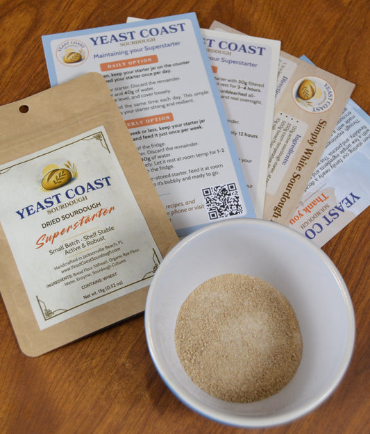 Yeast Coast dried sourdough starter packaging inserts with a bowl of starter on a wooden surface