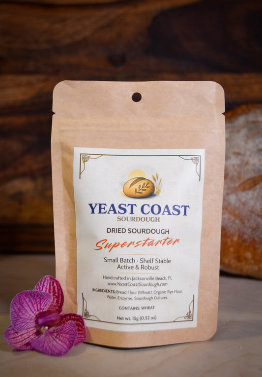 Yeast Coast Dried Sourdough Superstarter package with a purple orchid on a wooden background