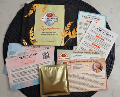 Yeast Coast sourdough starter kit with various packets and documents on a black plate.
