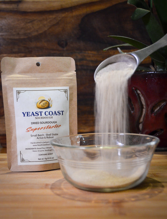 Yeast Coast dried sourdough superstarter being poured into a glass bowl with a wooden background.