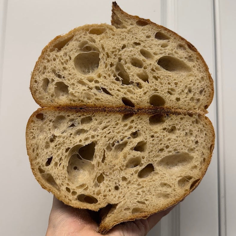 Hand holding a sliced loaf of bread against a white cabinet background
